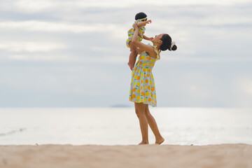 Mother holding baby with happy moments at sea in the evening