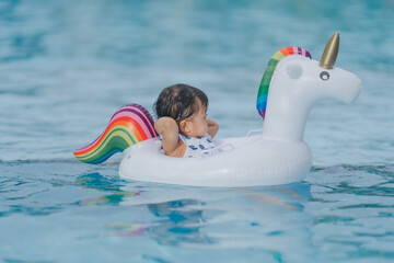 The baby is very happy playing in the pool on vacation. by sitting in a rubber ring