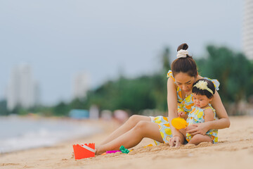 Mother and baby having a happy time at sea by lounging on the beach to teach learning and development.