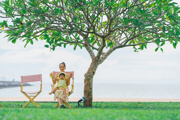 Mother and baby in yellow floral dresses with moments of happiness, smiles and happiness on vacation by traveling to the sea.