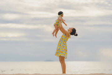 Mother holding baby with happy moments at sea in the evening