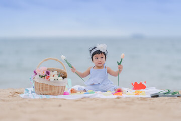 A cute baby is happy on a bright and early morning day on the beach while enjoying the concept picnic with fun emotions and learning along the way.