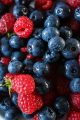 Delicious juicy ripe wild berries raspberries and blueberries in colorant. Washed berries for breakfast