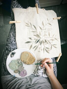 Overhead View Of A Woman Hand Painting A Tote Bag