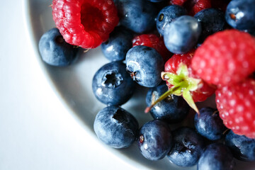 Delicious juicy ripe wild berries raspberries and blueberries in colorant. Washed berries for breakfast