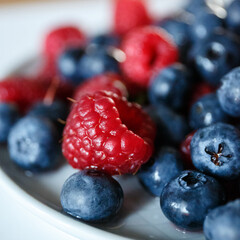 Delicious juicy ripe wild berries raspberries and blueberries in colorant. Washed berries for breakfast