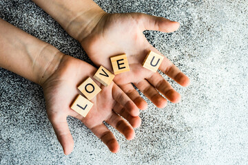 Overhead view of hands holding wooden blocks spelling love u