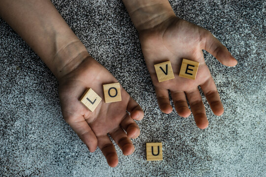 Overhead view of hands holding wooden blocks spelling love u