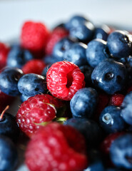 Delicious juicy ripe wild berries raspberries and blueberries in colorant. Washed berries for breakfast