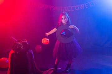 Little girl holds pumpkin jack on Halloween holiday. Kid girl wear witch costume. Fantasy, fairy tale and masquerade concept.