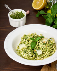 Traditional italian pasta pesto with pine nuts, pound garlic, basil leaves, hard parmesan cheese, lemon and extra-virgin olive oil. Mediterranean pesto sauce and spaghetti. Tasty homemade vegetarian
