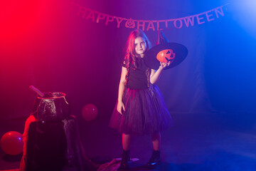 Little girl holds pumpkin jack on Halloween holiday. Kid girl wear witch costume. Fantasy, fairy tale and masquerade concept.