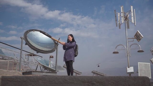 Girl lights a wooden stick with Solar Heliostats.