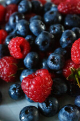 Delicious juicy ripe wild berries raspberries and blueberries in colorant. Washed berries for breakfast