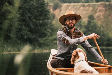 Hapy man and dog rowing the canoe on the river