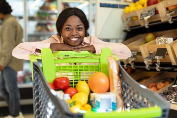African American Woman Posing With Shop Cart In Modern Supermarket