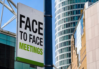 Naklejka premium Face to Face meetings sign in Downtown city setting