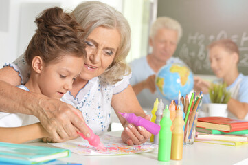 Portrait of grandmother and granddaughter drawing together