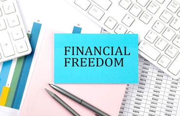 FINANCIAL FREEDOM text on blue sticker on chart with calculator and keyboard,Business concept