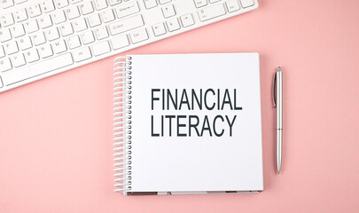 Pink office desk with keyboard and notebook with text FINANCIAL LITERACY