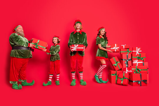 Full length body size view of nice cheerful friends elf holding festal eve giftboxes isolated over bright red color background