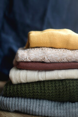 Pile of colorful sweaters in warm tones. Selective focus.