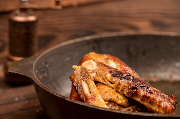 Pieces of roast duck with spices in a frying pan, close-up, selective focus.