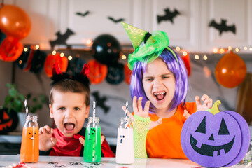 Scary drinks in funny bottles for a Halloween party and funny toddler kids in carnival costume. Traditions, holidays, treats concept.