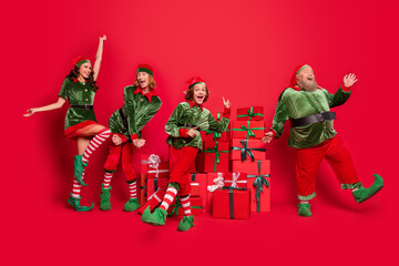 Full length body size view of cheerful friends elf having fun festal sale boxes dancing isolated over bright red color background
