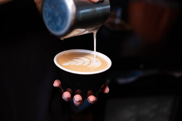 latte art by barista. pouring milk in coffee. dark coffee house