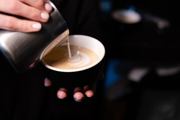 Fototapeta na wymiar latte art by barista. pouring milk in coffee. dark coffee house.