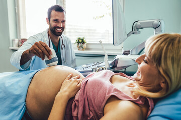 Obstetrician examining pregnant woman belly by ultrasonic scan in hospital.