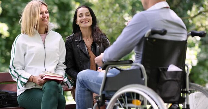 Disabled man in wheelchair communicating with friends in park 4k movie
