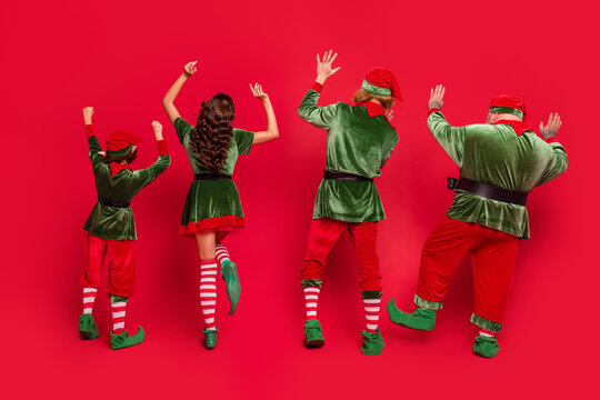 Back rear spine view full size photo of people elf enjoy raise hands dance christmas xmas isolated on red color background
