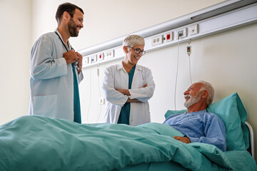 Doctor talking to senior male patient in hospital bed who is recovering from the disease