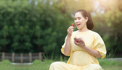 Pregnant woman eating strawberry resting outdoor