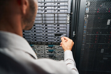 Unrecognized European maintenance administrator examining supercomputer in serber room