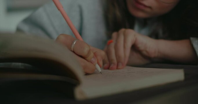 Soft focus shot of young woman write notes in small paper notebook, work on project or idea, fill out assignment for homework in university or school. Study or work from home