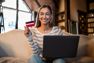 Fototapeta na wymiar Smiling woman using credit card and pc