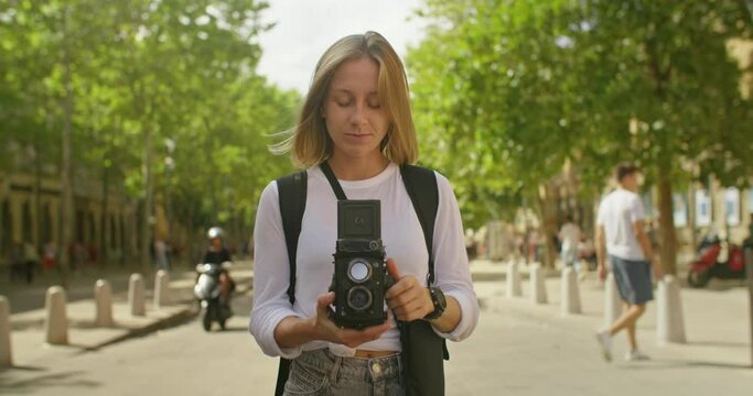 Young cute woman make photo on vintage analog camera. Female tourist use medium format film camera to capture vacation memories. Cinematic and inspiring millennial holiday vibes