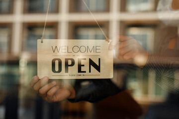 Close up of  Store owner turning open sign broad through the door glass and ready to serve. hotel service, cafe-restaurant, retail store, small business owner concept 