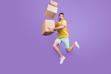 Full body profile side photo of young guy jump hold boxes air postal service isolated over purple...