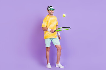 Full body photo of young guy happy positive smile training sporty fly ball isolated over purple color background