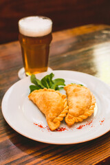 plate menu with Argentine empanadas with beer on a table in a night bar