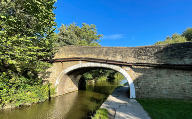Fototapeta na wymiar Victorian arched stone bridge, crossing over the, Leeds to Liverpool canal near, Dobb Kiln Lane, Bingley, UK