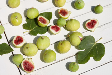 Fresh green figs with leaves on white wooden table