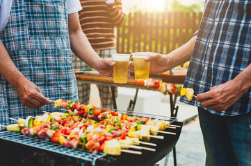 Cheers! Cheers to a group friends drinking beer at an outdoor BBQ party.