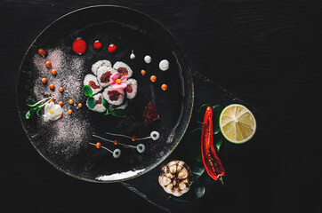 sushi roll in plate on black wooden table background. top view