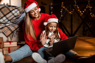 Happy festive woman and daughter using pc making videocall