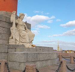 Sculpture at the base of the Rostral column on the Spit of Vasilievsky Island. Peter and Paul Fortress in the background. Saint Petersburg, Russia.